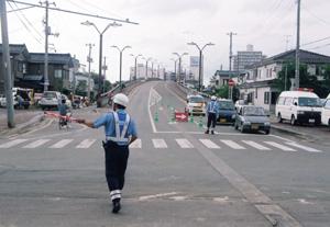 信号機が使用できない為、手信号にて道路の交通規制をする警察