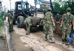 細い小路のごみを排除する自衛隊員の写真