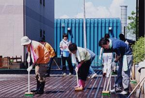 三条市災害ボランティアセンター達さん達がデッキブラシを手に清掃している写真