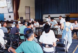 災害見舞い金の配布会場となった月岡小学校。手続きを待つ人々と一人ひとり対応している職員の写真