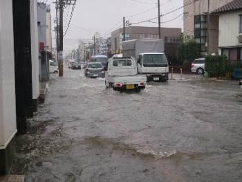 冠水した道路を走る車の写真
