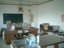 水道のついたステンレスの調理台や黒板がある料理実習室の写真