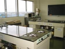 複数の調理台や黒板などがある料理実習室の写真