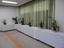 白布を敷いたテーブルの上に飾られた生花作品6点