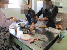調理台でベーコンの漬け液を入れたビニール袋に肉を入れている男女3人