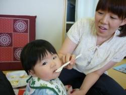 お母さんが赤ちゃんの口にスプーンで離乳食を食べさている写真