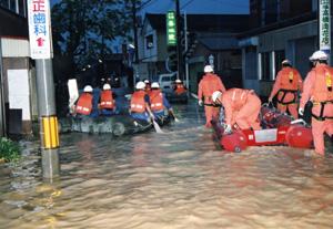 膝丈まで浸水し、ゴムボートに乗りながら救急隊員が救助作業をしている御蔵橋南の様子の写真