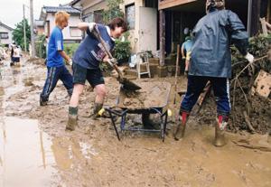 懸命に家に入った汚泥のかき出しを行うボランティアスタッフ達の写真